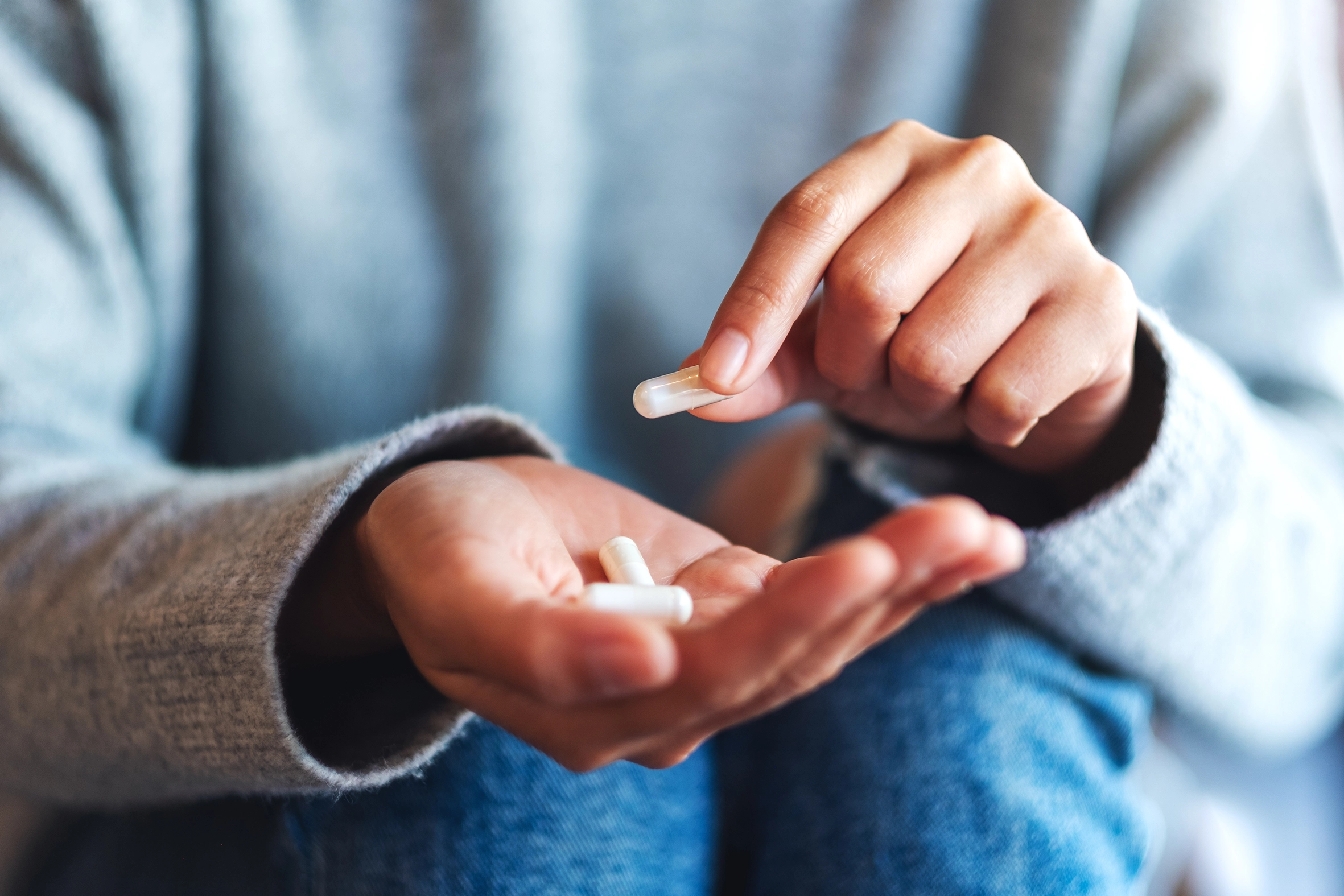 woman showing three white compounded capsules