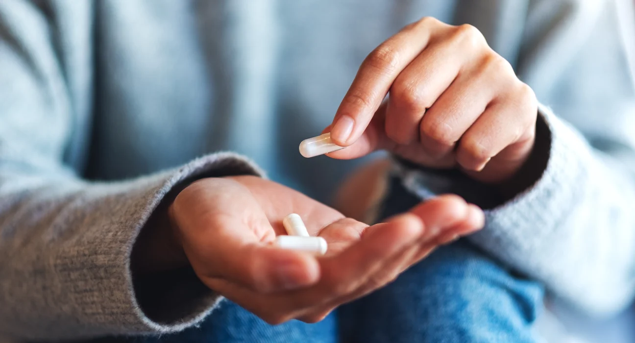 woman showing three white compounded capsules